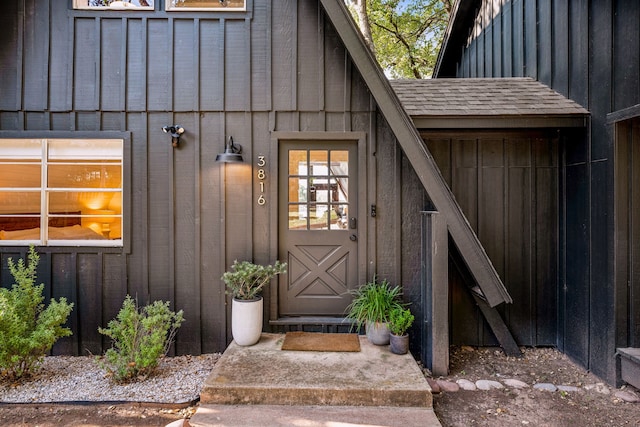 property entrance featuring roof with shingles and board and batten siding