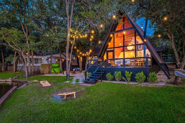 rear view of property featuring stairs, fence, and a yard