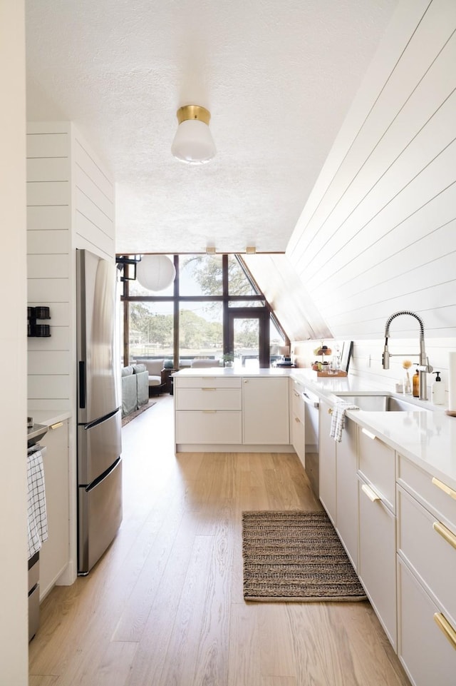 interior space with a textured ceiling, a sink, and light wood-type flooring