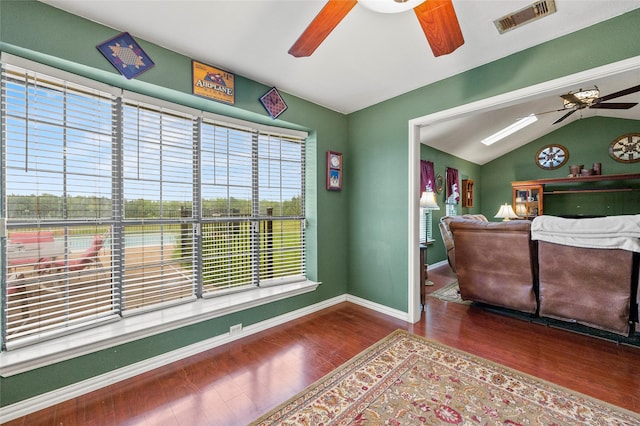 interior space featuring visible vents, wood finished floors, baseboards, a ceiling fan, and vaulted ceiling