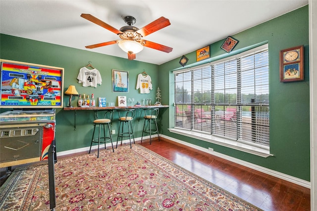bar featuring baseboards, ceiling fan, and wood finished floors