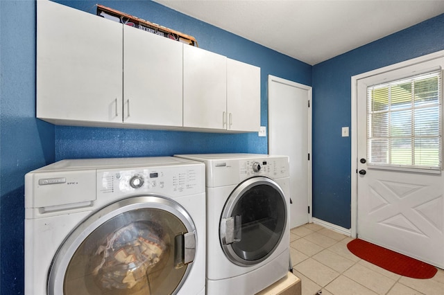 clothes washing area with light tile patterned floors, separate washer and dryer, baseboards, and cabinet space