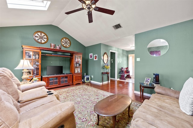 living area with visible vents, wood finished floors, baseboards, ceiling fan, and vaulted ceiling with skylight