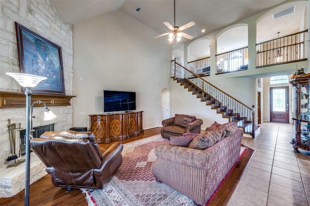 living room with visible vents, a ceiling fan, stairs, and high vaulted ceiling