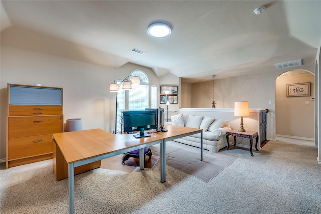 office area with visible vents, arched walkways, vaulted ceiling, and light carpet