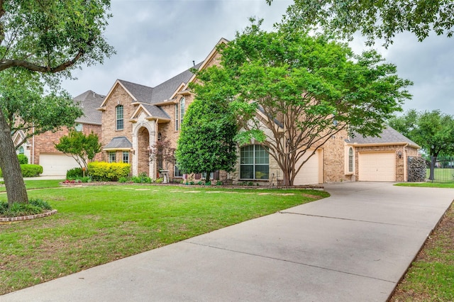 traditional-style home featuring a garage, a front lawn, fence, brick siding, and concrete driveway