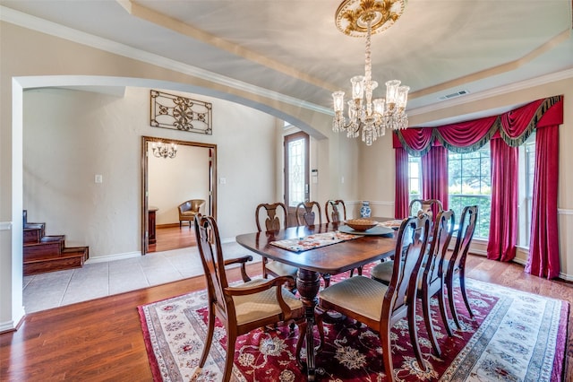 dining room with arched walkways, visible vents, wood finished floors, and a raised ceiling