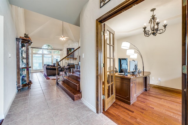 hall featuring baseboards, lofted ceiling, a notable chandelier, and stairway