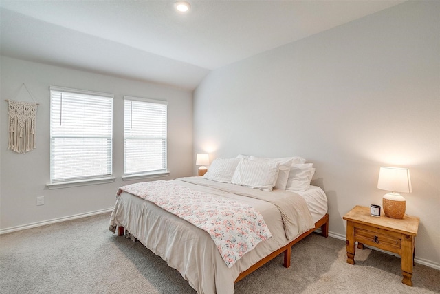 bedroom with baseboards, vaulted ceiling, and light carpet