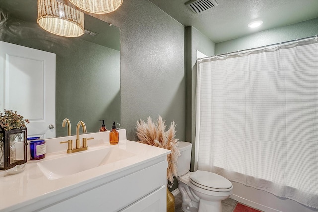 bathroom featuring visible vents, vanity, a textured wall, toilet, and shower / tub combo