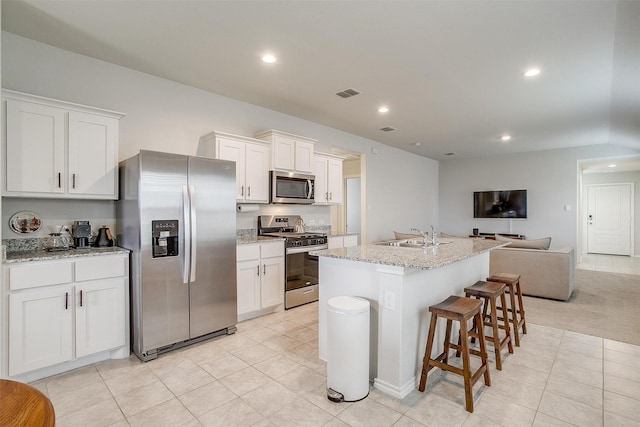 kitchen with visible vents, open floor plan, white cabinets, a sink, and appliances with stainless steel finishes