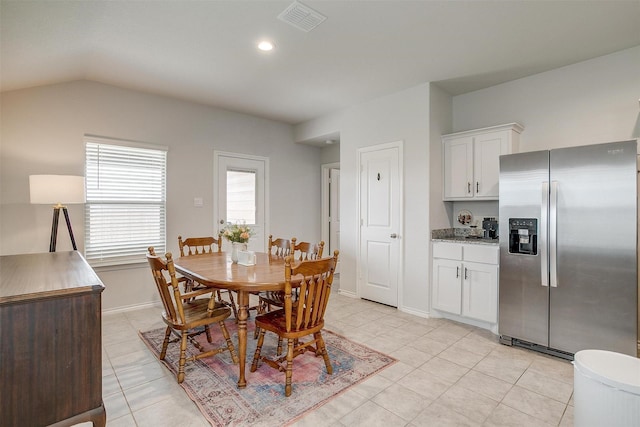 dining space featuring baseboards, visible vents, light tile patterned floors, and vaulted ceiling