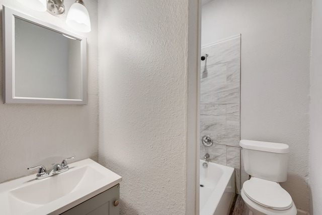 bathroom featuring vanity, a textured wall, bathing tub / shower combination, and toilet