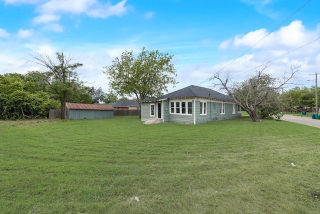 view of yard featuring a storage shed, fence, an outbuilding, and entry steps