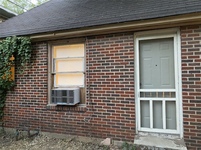 view of property exterior with brick siding, a shingled roof, and cooling unit