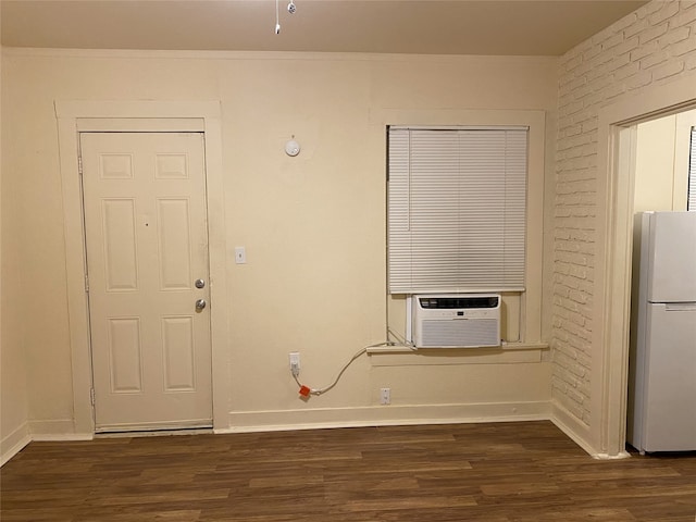 entryway featuring wood finished floors, baseboards, cooling unit, and brick wall
