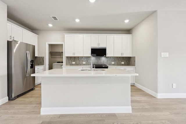 kitchen featuring stainless steel fridge, a sink, light countertops, tasteful backsplash, and visible vents