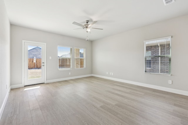 spare room featuring visible vents, a ceiling fan, light wood-style flooring, and baseboards