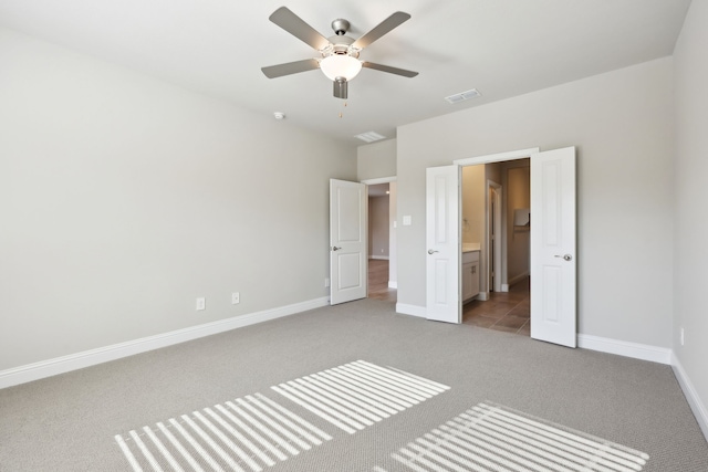 unfurnished bedroom featuring visible vents, light carpet, baseboards, ensuite bathroom, and ceiling fan
