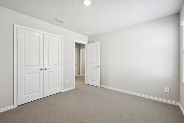 unfurnished bedroom with baseboards, visible vents, carpet, and a closet