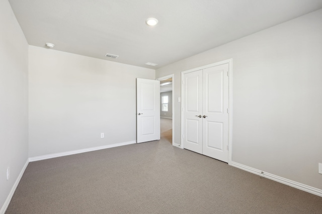 unfurnished bedroom with baseboards, carpet floors, visible vents, and a closet