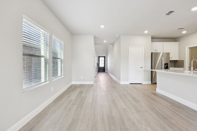 unfurnished living room with visible vents, recessed lighting, light wood-style floors, and baseboards