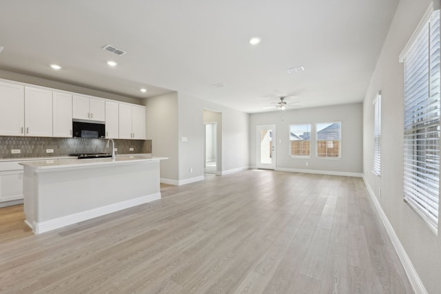 kitchen featuring decorative backsplash, ceiling fan, visible vents, black microwave, and light wood finished floors