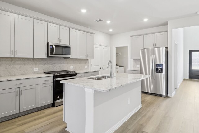 607 Willet Dr, Mckinney, TX 75069 - kitchen featuring appliances with stainless steel finishes, a sink, a kitchen island with sink, decorative backsplash, and visible vents