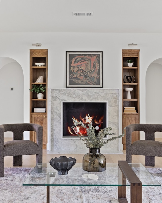dining room with arched walkways, visible vents, built in features, and a high end fireplace