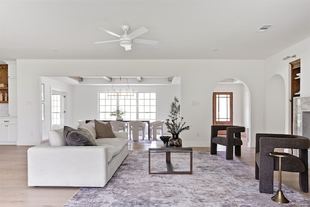 living room featuring a healthy amount of sunlight, arched walkways, light wood-style flooring, and visible vents