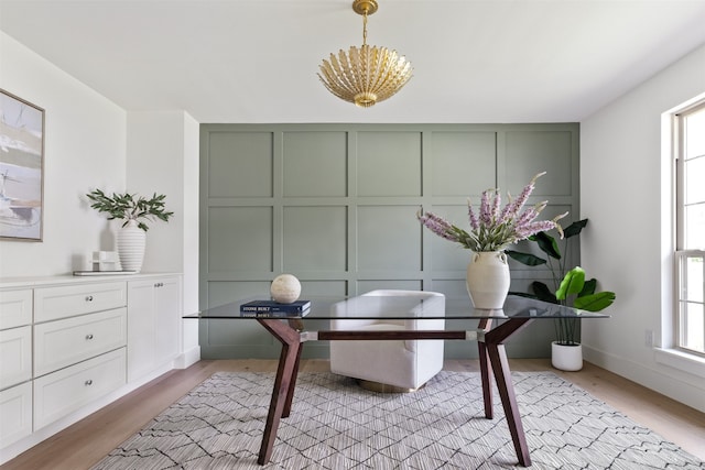 home office featuring an inviting chandelier, light wood-style flooring, and a decorative wall