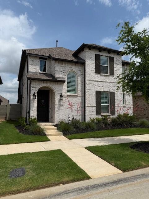 french country inspired facade with a front lawn and brick siding