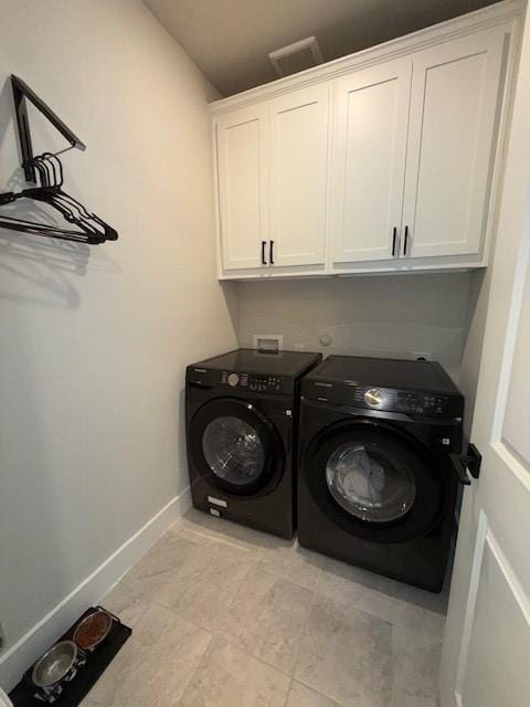 washroom with baseboards, visible vents, cabinet space, and washer and dryer