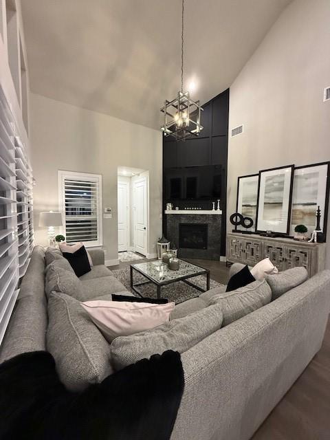 living area featuring high vaulted ceiling, visible vents, an inviting chandelier, and a fireplace