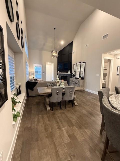 dining space featuring a chandelier, high vaulted ceiling, visible vents, and dark wood finished floors