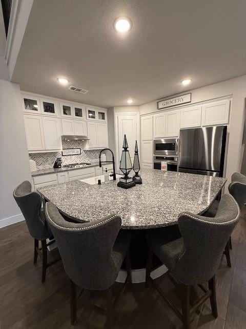kitchen with visible vents, decorative backsplash, white cabinetry, and stainless steel appliances