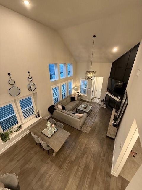 living room featuring high vaulted ceiling, a notable chandelier, dark wood-style floors, and baseboards