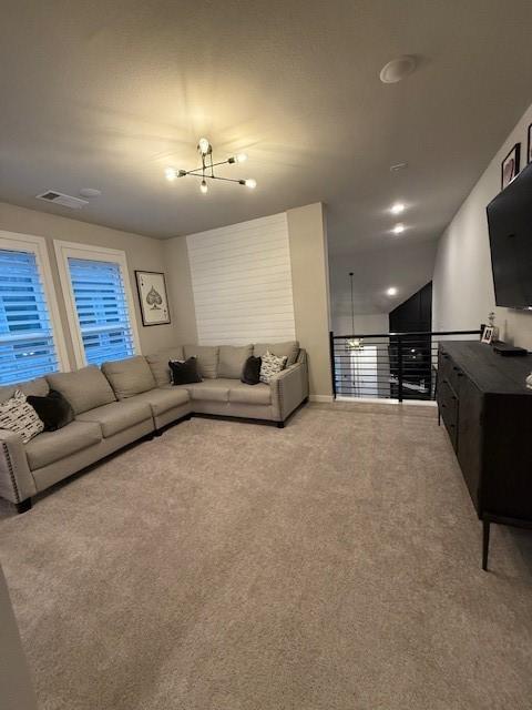 carpeted living room with a chandelier and visible vents