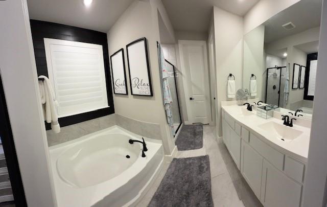 bathroom with a garden tub, tile patterned flooring, double vanity, a sink, and a stall shower