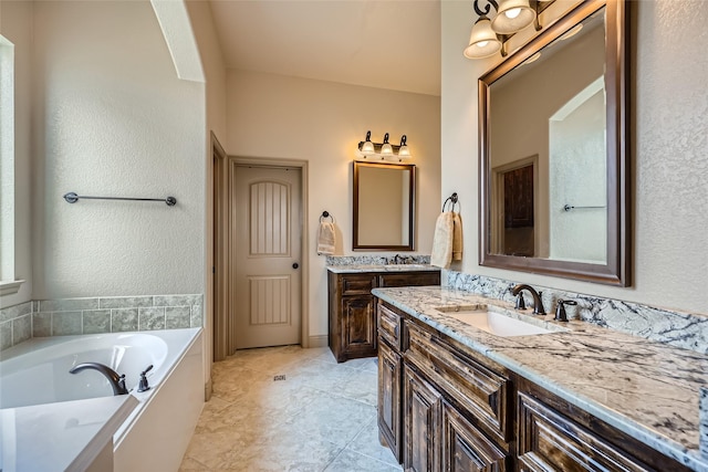 full bath featuring two vanities, a sink, and a garden tub