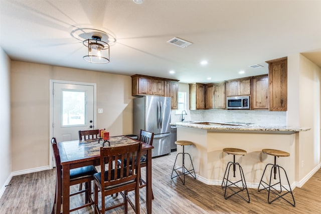 140 Tnt Ct, Springtown, TX 76082 - kitchen with visible vents, light wood-style flooring, backsplash, and stainless steel appliances
