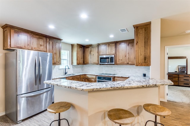 140 Tnt Ct, Springtown, TX 76082 - kitchen with visible vents, light stone counters, a sink, light wood finished floors, and appliances with stainless steel finishes