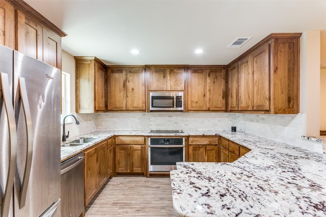140 Tnt Ct, Springtown, TX 76082 - kitchen with appliances with stainless steel finishes, a sink, brown cabinetry, light wood-style flooring, and visible vents
