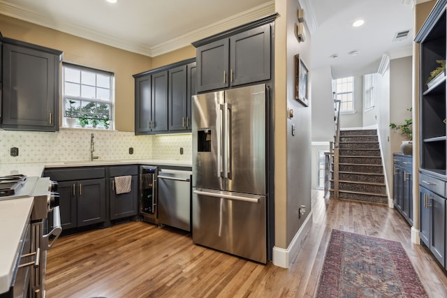 5102 Ridgedale Ave, Dallas, TX 75206 - kitchen with appliances with stainless steel finishes, ornamental molding, a sink, decorative backsplash, and light wood-type flooring