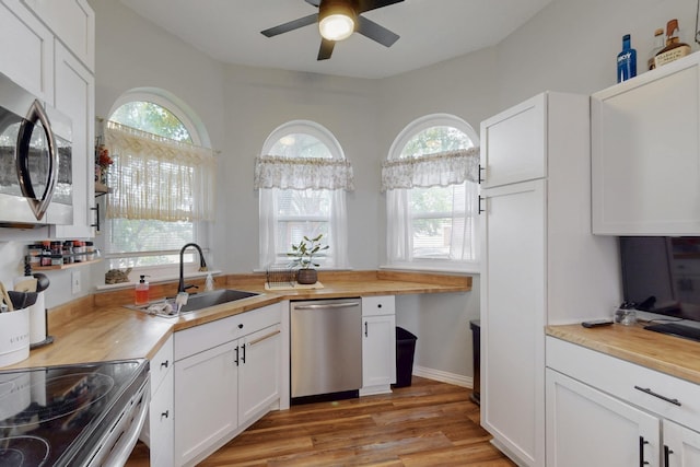 kitchen with a ceiling fan, appliances with stainless steel finishes, wooden counters, and a sink