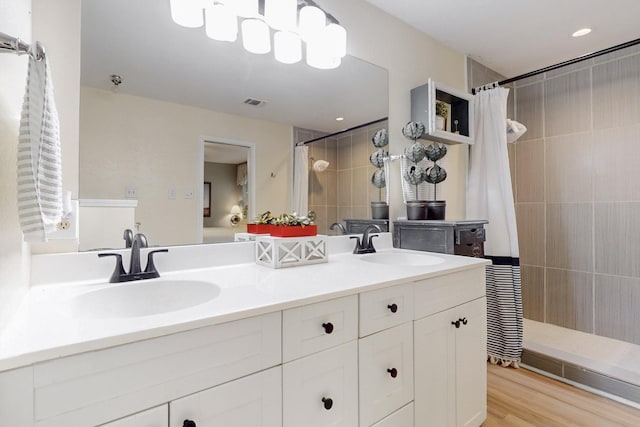 bathroom with double vanity, a sink, and tiled shower