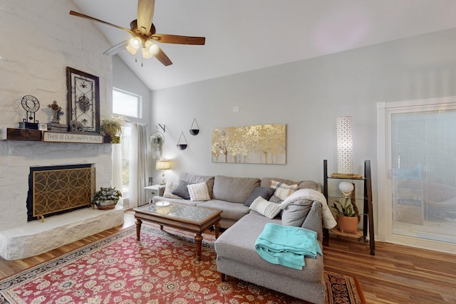 living room with ceiling fan, wood finished floors, a premium fireplace, and high vaulted ceiling