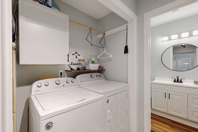 clothes washing area featuring separate washer and dryer, laundry area, light wood-style floors, and a sink