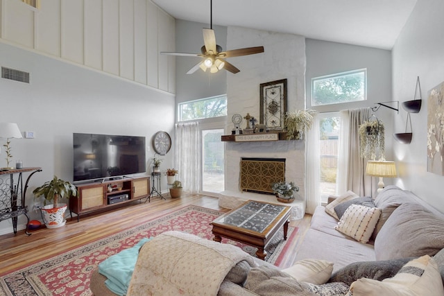 living area with visible vents, wood finished floors, and high vaulted ceiling