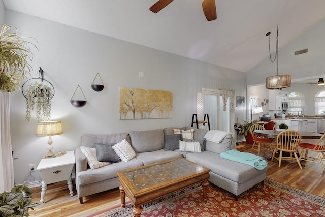 living area featuring ceiling fan, visible vents, high vaulted ceiling, and light wood-style floors